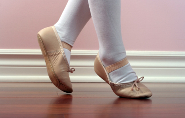 ankles and feet with ballet tights and ballet shoes on a wood floor